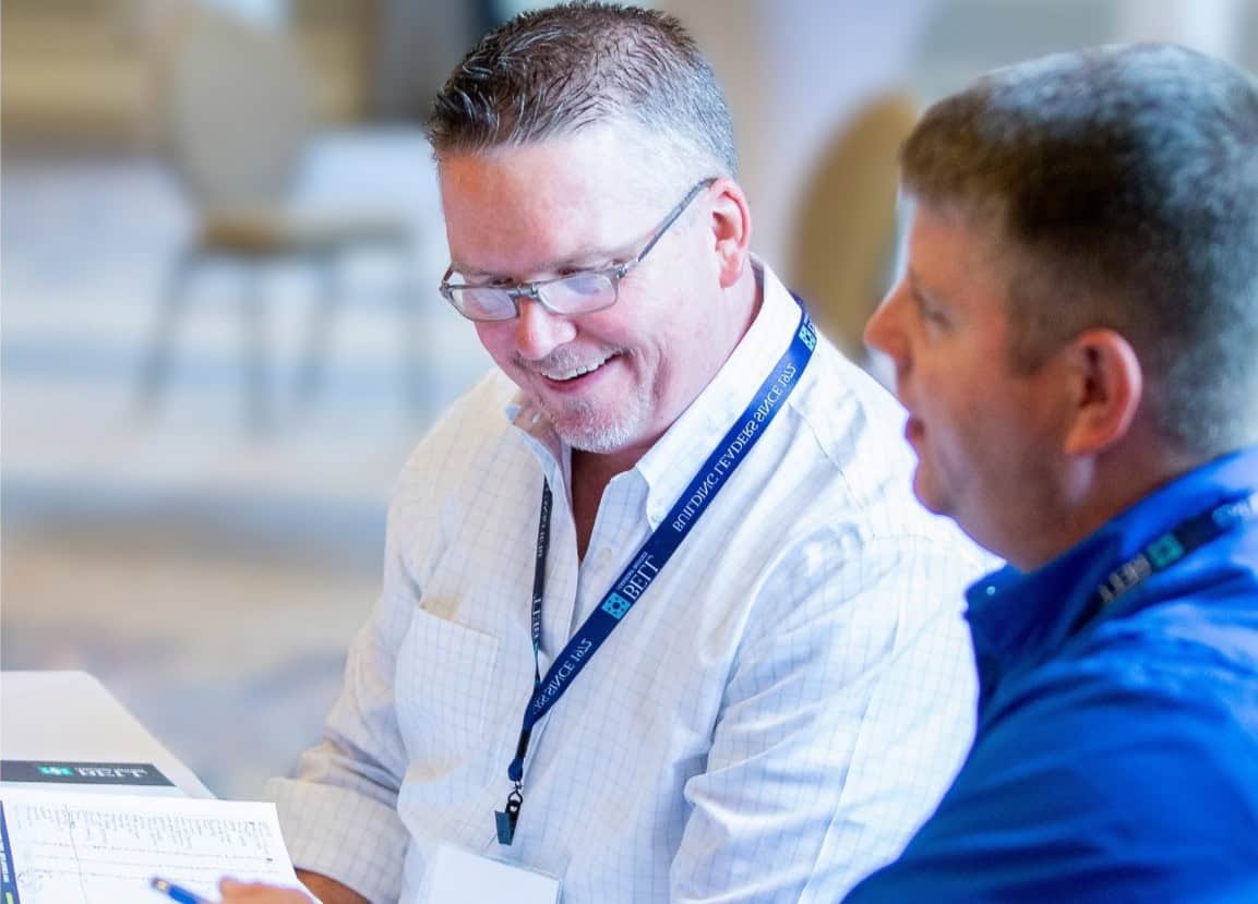 Two Bell Leadership program participants talking with each other and looking at papers.