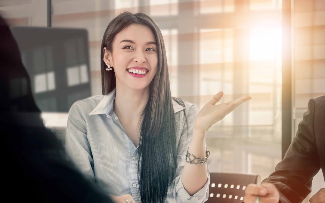 Woman sitting at office table, smiling with sunlight coming in.