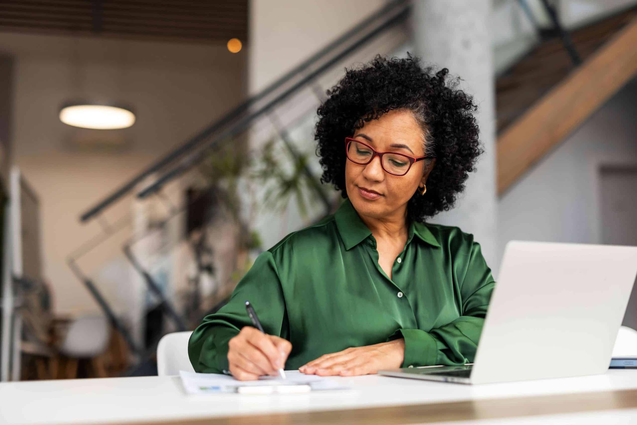 Woman sitting at office table, smiling with sunlight coming in.